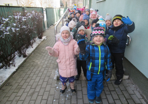 Dzieci stoją w parach przed budynkiem przedszkola.