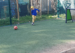 chłopiec gra w piłkę na boisku przedszkolnym