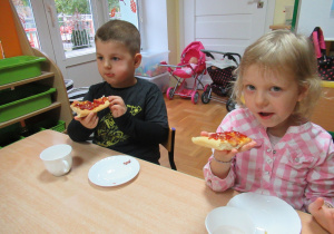 Chłopiec i dziewczynka jedzą pizze.