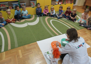 Dzieci siedzą na dywanie podczas warsztatów Labo.