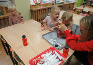 Dzieci siedzą przy stoliku i wykonują pracę sensoryczną podczas warsztatów.