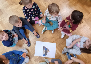 Dzieci siedzą na podłodze i układają puzzle z budowlami Wloch.
