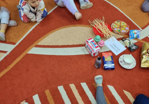 Dzieci siedzą na dywanie i oglądają smakołyki kuchni wloskiej.