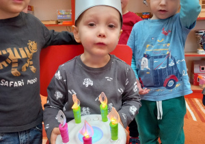 Chłopiec ma srebrną koronę i trzyma tort z plastiku.