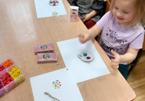 Dzieci wyklejają papierowe kółka kolorową plasteliną.
