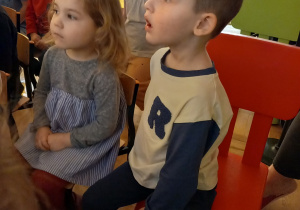 Chłopiec i dziewczynka siedza na krzesełkach.