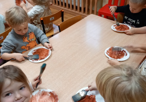 Dzieci malują na brązowo papierowe talerzyki.