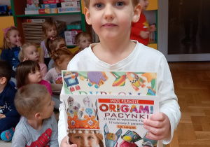Chłopiec pokazuje książkę.