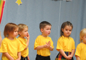 Dzieci ubrane w żółte koszulki śpiewają piosenką.
