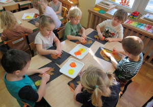 Dzieci malują farbami za pomocą gąbeczki.