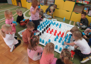Dzieci układają kolorowe kubeczki na macie do kodowania, układają flagę Polski.