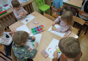 Dzieci przy stoliku bawią się plasteliną.