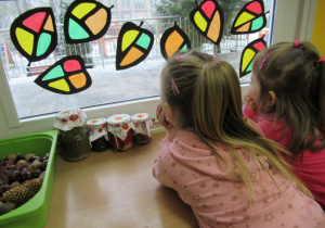 Dziewczynki patrzą przez okno jak pada śnieg.