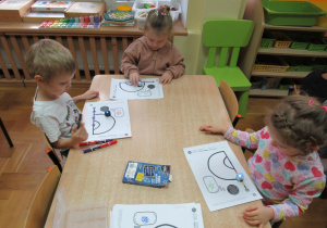 Dzieci siedzą przy stoliku i obserwują jak poruszają się roboty Ozoboty.