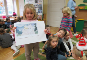 Dziewczynka pokazuje obrazek ułożony z części.