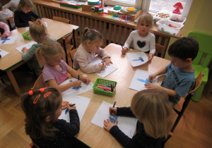 Dzieci przy stolikach kolorują flagę Finlandii.