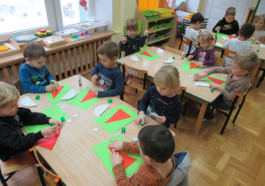 Dzieci przy stolikach wykonują prace plastyczne.