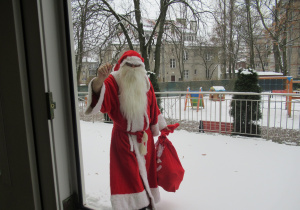 Święty Mikołaj idzie z workiem pełnym prezentów.