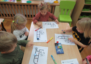 Dzieci przy stolikach obserwują roboty Ozoboty.