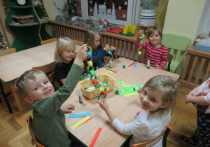 Dzieci przy stoliku robią łańcuchy z papieru.