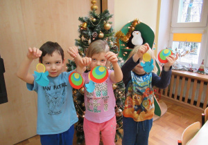 Dzieci prezentują wykonane ozdoby choinkowe - pawie oczka i aniołki.