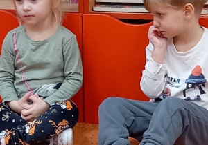 chłopiec i dziewczynka siedzą na czerwonym dywanie.