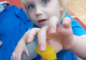 Chłopiec pokazuje żółtą kostkę.