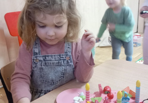 Dziewczynka bawi się drewnianym tortem.