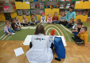 Dzieci siedzą na dywanie podczas warsztatów Labo.