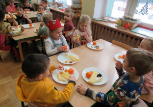 Dzieci siedzą przy stolikach i zjadają urodzinowe drugie śniadanie.
