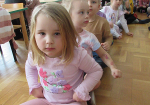 Dzieci siedzą na podłodze tworząc "pociąg".