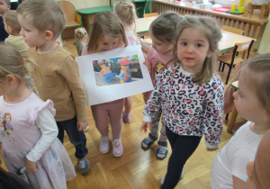 Dziewczynka prezentuje obrazek przedstawiający ludziki Lego.