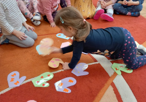 Dzieci układają na dywanie obrazki z rękawiczkami.