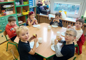 Dzieci jedzą pączki z okazji "tłustego czwartku"