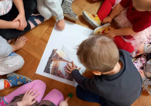 Dzieci naklejają obrazek Wieży Eiffla na kartce.