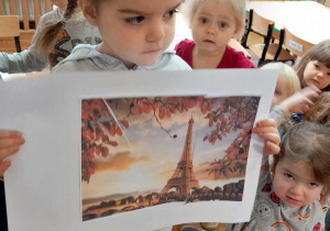 Dziewczynka pokazuje zdjęcie Wieży Eiffla.
