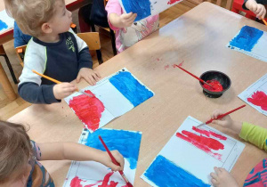 Dzieci malują farbami flagę Francji.