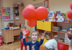 Dziewczynka podrzuca czerwony balon.