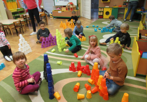 Dzieci budują wieże z kolorowych kubeczków.