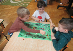 Chłopcy siedzą przy stoliku i grają w grę.