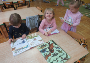 Dziewczynki oglądają książki o dinozaurach.