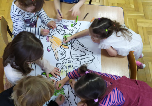 Dzieci podczas kolorowania kolorowanki o dinozaurach