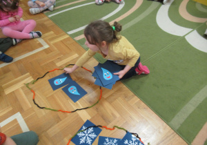 Dziewczynka układa obrazki z kropelkami w obręczy.
