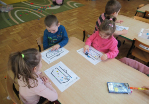 Dzieci siedzą przy stoliku i obserwują jak porusza się robot Ozobot.