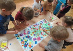 Dzieci malują farbami kwiaty.