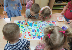 Dzieci malują farbami łąkę.