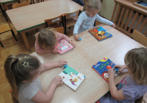 Dzieci siedzą przy stole i mierzą książki.