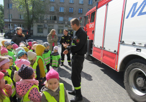 Dzieci stoją przed strażakiem i słuchają.