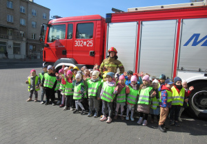 Dzieci pozują do zdjęcia ze strażakiem.