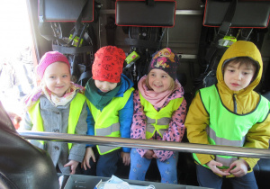 Dzieci siedzą w wozie strażackim.